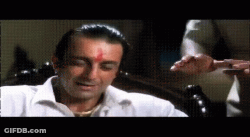 A Man In A White Shirt With A Red Spot On His Forehead Is Sitting On A Chair . GIF