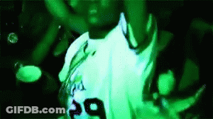 A Man In A White Shirt With The Number 29 On It Is Dancing In A Green Light . GIF