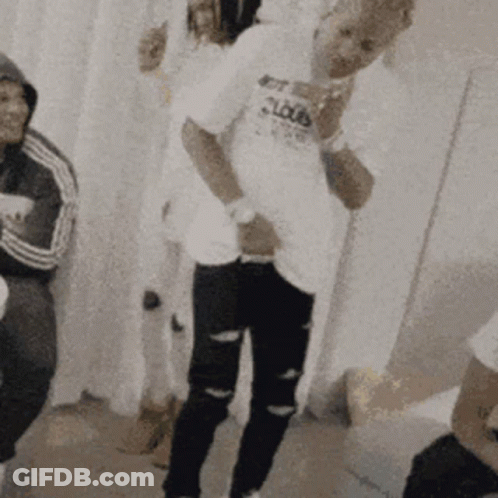 A Man In A White Shirt With The Word Clouds On It Is Standing In A Room With Other People . GIF