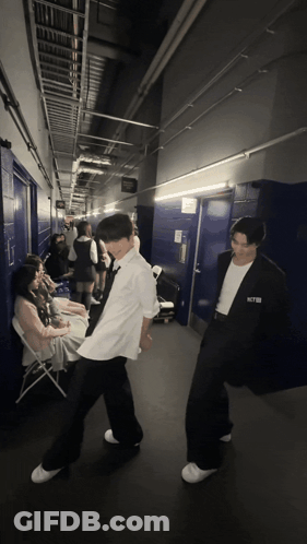 A Man In A White Shirt With The Word Nct On It Stands In A Hallway GIF