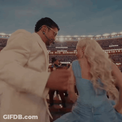 A Man In A White Suit And A Woman In A Blue Dress Are Dancing GIF