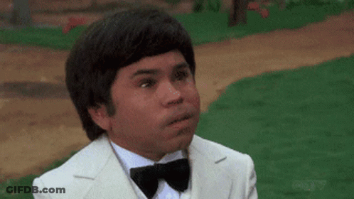 A Man In A White Suit And Bow Tie Is Making A Funny Face GIF