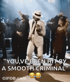 A Man In A White Suit And Hat Is Dancing With A Group Of People . GIF