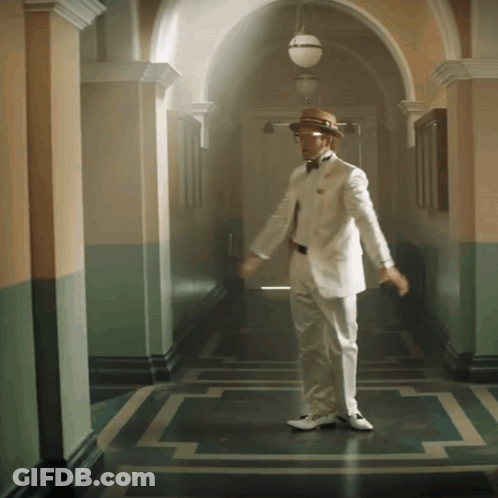 A Man In A White Suit And Straw Hat Is Dancing In A Hallway GIF