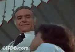 A Man In A White Suit And Tie Is Kissing A Woman . GIF