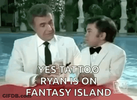 A Man In A White Suit And Tie Is Sitting Next To A Boy In A Tuxedo . GIF