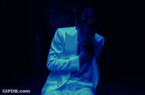 A Man In A White Suit Covering His Face With His Hand GIF