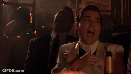 A Man In A White Suit Is Laughing With Another Man In A Black Suit Behind Him GIF