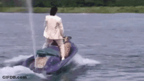 A Man In A White Suit Is Riding A Jet Ski On A Lake . GIF