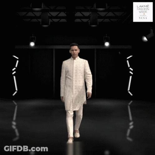 A Man In A White Suit Is Standing In Front Of A Lakme Fashion Week Sign GIF