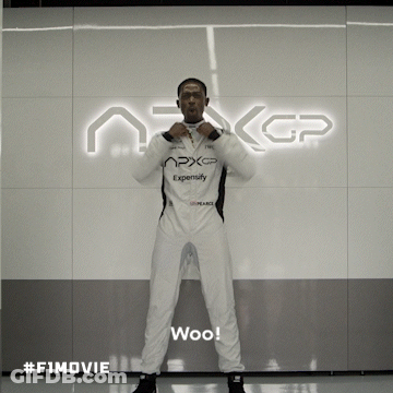 A Man In A White Suit Stands In Front Of A Sign That Says Nxgp GIF