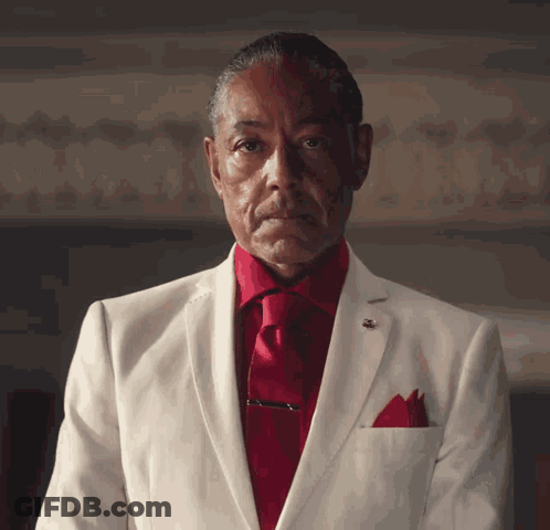 A Man In A White Suit With A Red Tie GIF