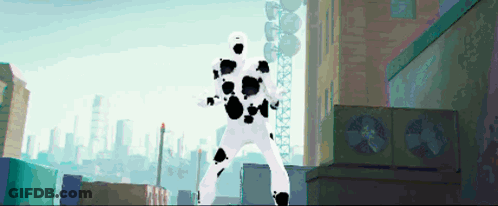 A Man In A White Suit With Black Spots Is Standing In A City GIF