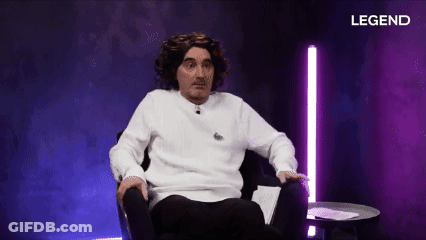 A Man In A White Sweater Is Sitting In A Chair In Front Of A Purple Background With Legend Written On It GIF