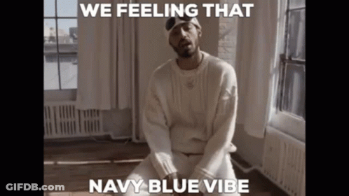 A Man In A White Sweater Is Sitting In Front Of A Window With The Caption " We Feeling That Navy Blue Vibe " GIF