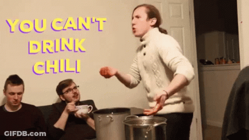 A Man In A White Sweater Is Standing In Front Of A Wall With The Words " You Can 'T Drink Chili " On It GIF