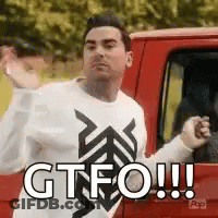A Man In A White Sweater Is Standing Next To A Red Truck And Making A Funny Face . GIF