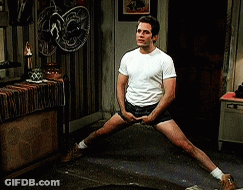 A Man In A White T-Shirt And Shorts Is Stretching His Legs . GIF