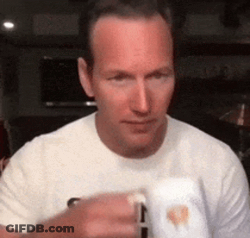 A Man In A White T-Shirt Is Holding A Mug In His Hand . GIF