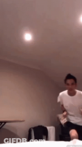 A Man In A White T-Shirt Is Jumping In The Air GIF