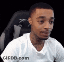 A Man In A White T-Shirt Is Sitting In A Chair . GIF