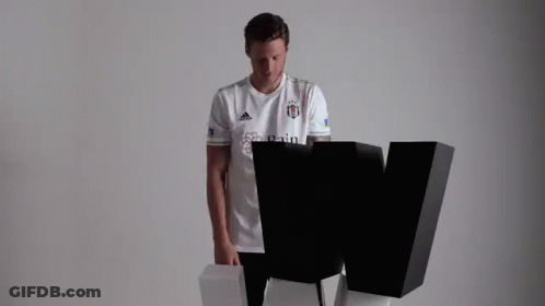 A Man In A White T-Shirt Is Standing Next To A Black Letter W . GIF