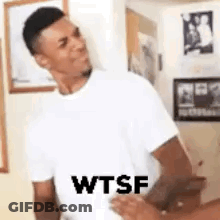 A Man In A White T-Shirt Is Standing Next To A Woman In A Room And Making A Funny Face . GIF