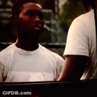 A Man In A White T-Shirt Is Standing Next To Another Man GIF