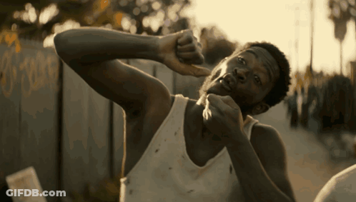 A Man In A White Tank Top Holds His Hand To His Face GIF