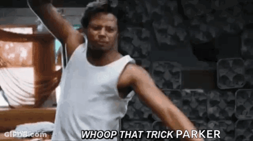 A Man In A White Tank Top Is Dancing In A Room With His Arms Outstretched . GIF