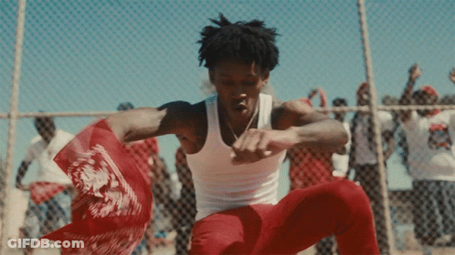 A Man In A White Tank Top Is Dancing In Front Of A Crowd GIF
