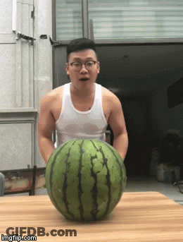 A Man In A White Tank Top Is Holding A Large Watermelon On A Table GIF