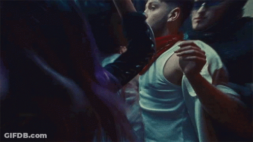 A Man In A White Tank Top Is Holding A Woman In A Crowd Of People GIF