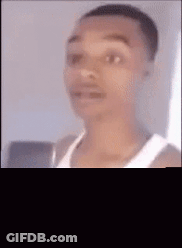 A Man In A White Tank Top Is Looking At The Camera . GIF