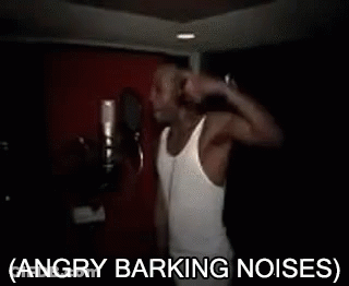 A Man In A White Tank Top Is Singing Into A Microphone With The Words Angry Barking Noises Below Him GIF