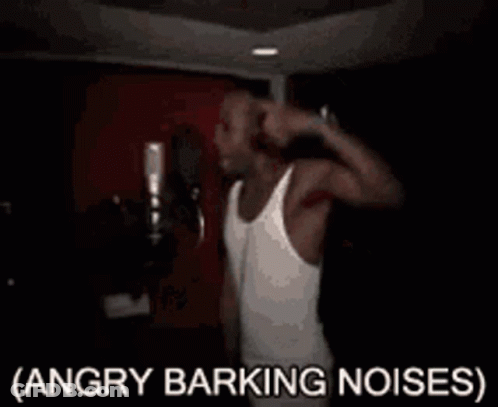 A Man In A White Tank Top Is Singing Into A Microphone With The Words Angry Barking Noises Written Below Him . GIF