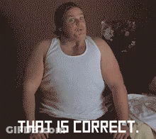 A Man In A White Tank Top Is Sitting On A Bed With The Words That Is Correct Behind Him GIF