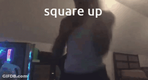A Man In A White Tank Top Is Standing In A Dark Room With The Words Square Up Written Above Him GIF