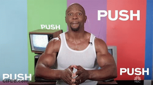A Man In A White Tank Top Is Standing In Front Of A Colorful Wall That Says Push GIF