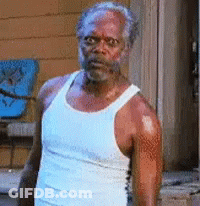 A Man In A White Tank Top Is Standing In Front Of A Door . GIF