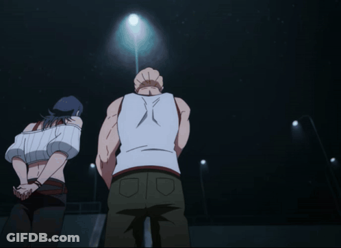 A Man In A White Tank Top Is Standing In Front Of A Woman GIF