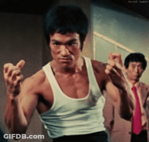 A Man In A White Tank Top Is Standing In Front Of Two Men In Suits And Ties GIF