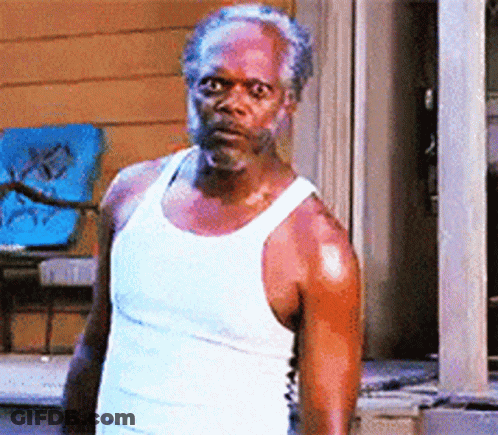 A Man In A White Tank Top Is Standing Outside GIF