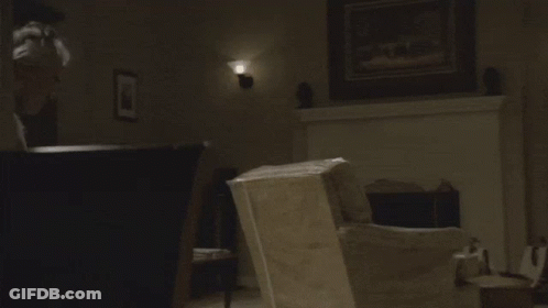 A Man In A White Tank Top Looks At Something GIF