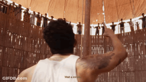 A Man In A White Tank Top Says Wait A Minute In Front Of A Crowd GIF
