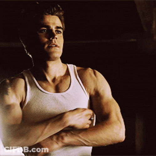 A Man In A White Tank Top Shows Off His Muscles GIF