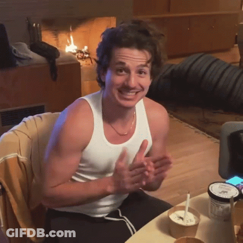 A Man In A White Tank Top Sits At A Table With A Bowl Of Ice Cream GIF