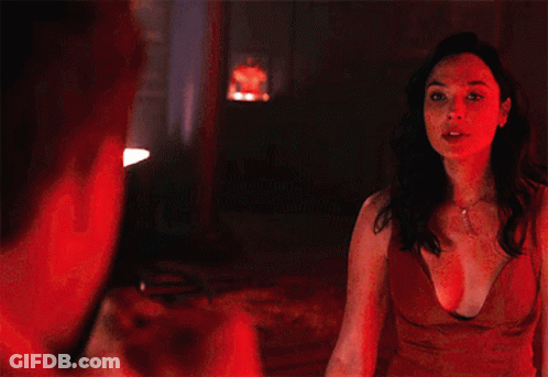 A Man In A White Tuxedo And Bow Tie Is Standing In A Dark Room GIF