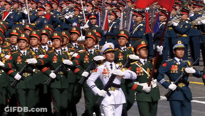 A Man In A White Uniform Stands In Front Of A Large Military March GIF