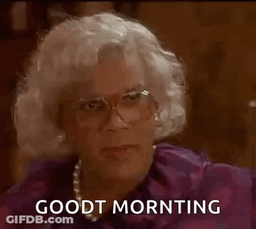 A Man In A Wig And Glasses Is Sitting Down And Saying `` Good Morning '' . GIF